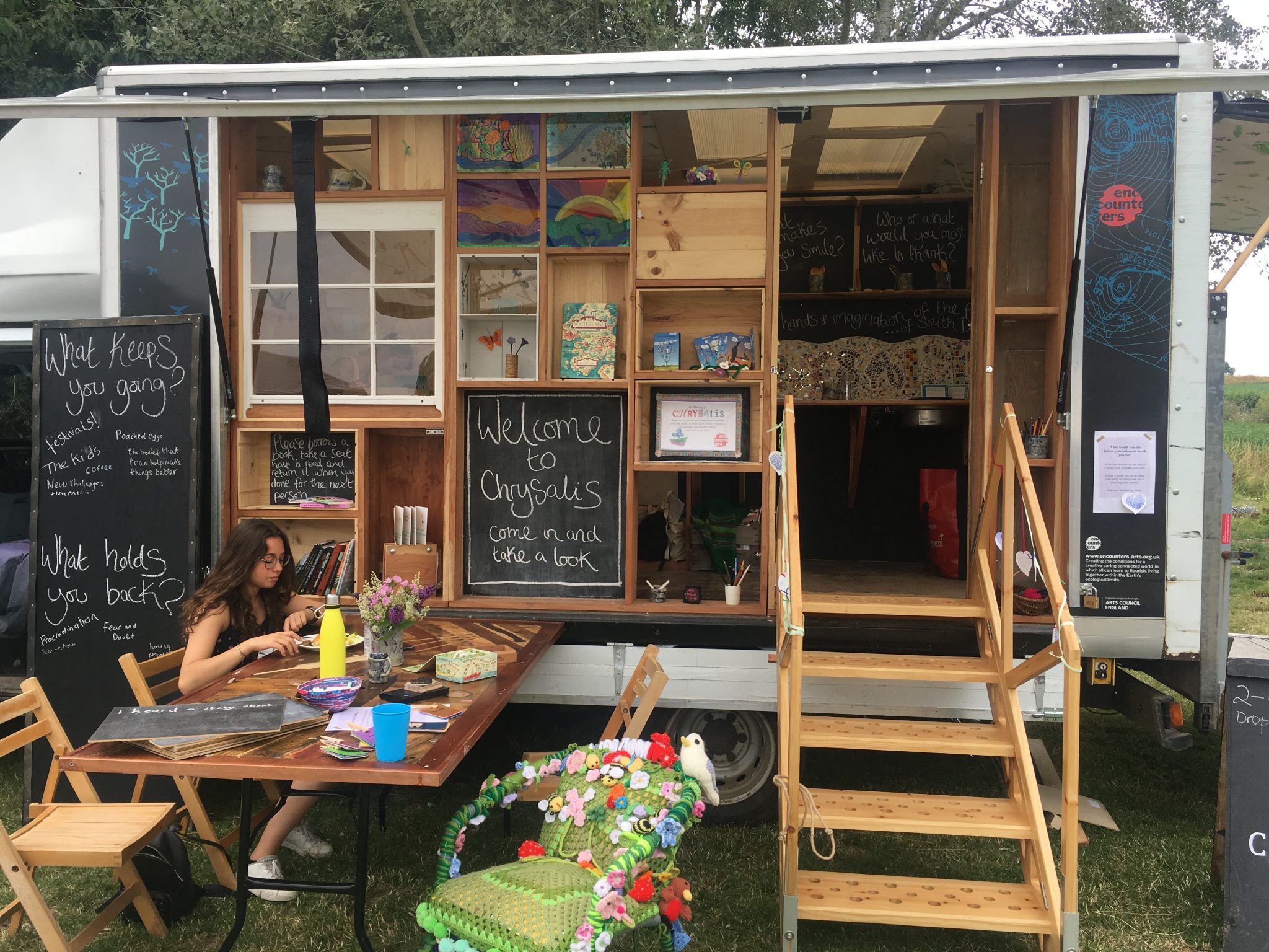 A small truck has been converted into a creative engagement space, with books, art, materials and questions on blackboards to prompt sharing and discussion. 