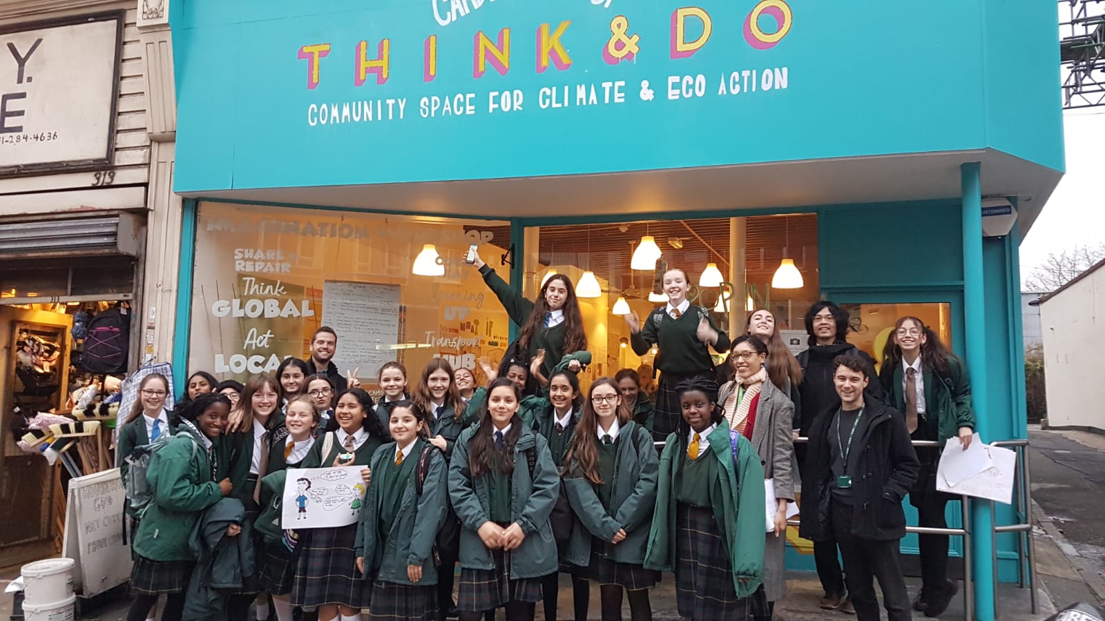 School children outside the original Think & Do pop up shop. The sign reads: "Camden Think & Do: community space for climate and eco action"