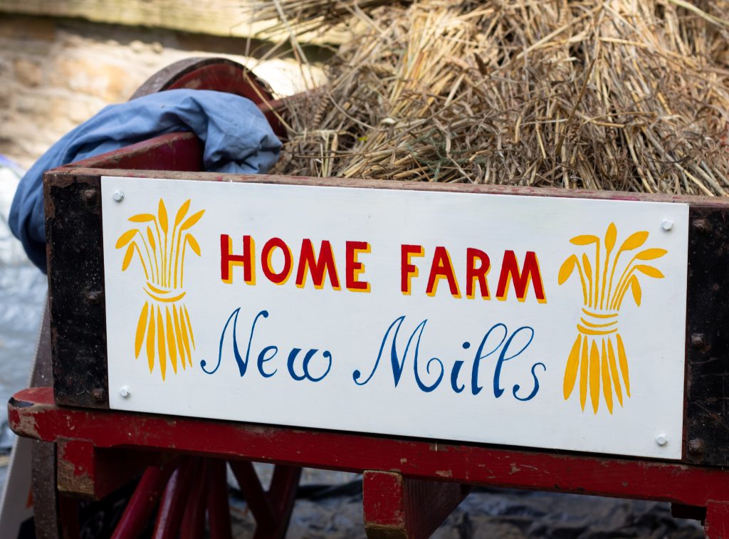 A cart full of wheat with a sign which reads "Home Farm New Mills"