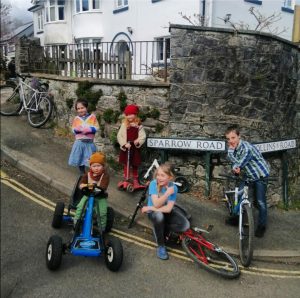 Give children on bikes, scooters and a pedal car hang about the corner of Sparrow Road during a street party.