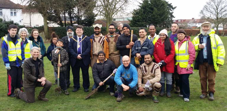 A group of around 20 volunteers including the Mayor, Park ranger, local youth and Transition Southall members pose for a group photo after planting trees in a local park. 
