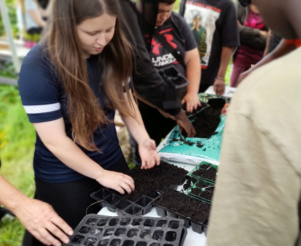 Young people fill seed trays with soil at a workshop at a community garden run by Transitoin group Community Roots Permaculture Project in Bolton.