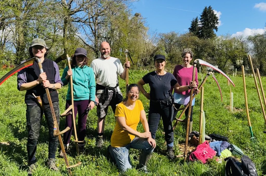 A group of gardeners from Transition Town WEllington with scythes to cut back the grass and allow wildflowers to thrive.